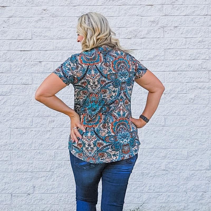 A woman wearing a short-sleeved paisley design shirt with a round neckline. shown in size medium