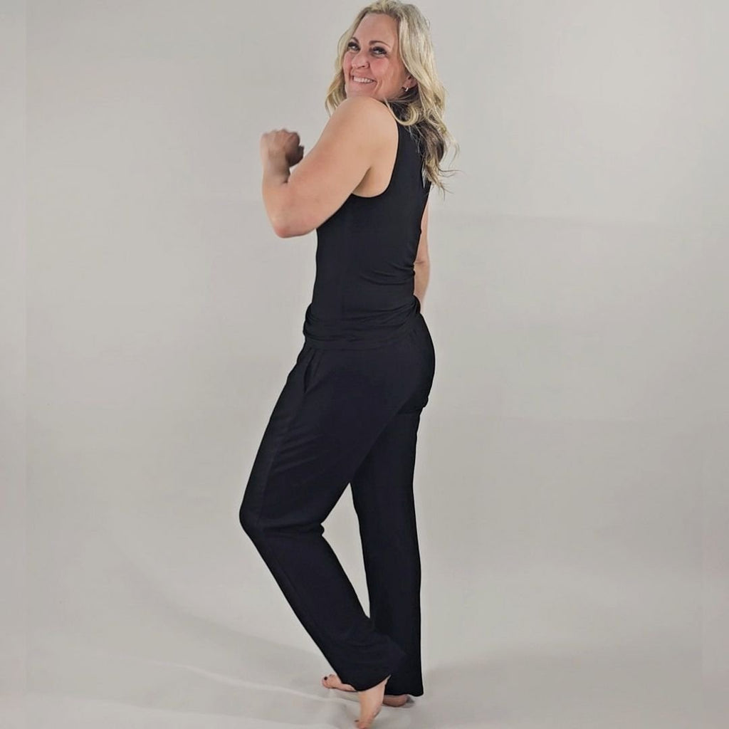 A woman wearing a black high-neck ribbed tank top. shown in size medium. paired with black ribbed wide leg pants in size medium. 