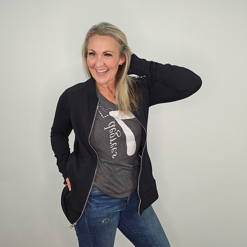 A woman wearing a black hoodless jacket with a stand collar, full front zipper, and thumbholes. shown in size medium