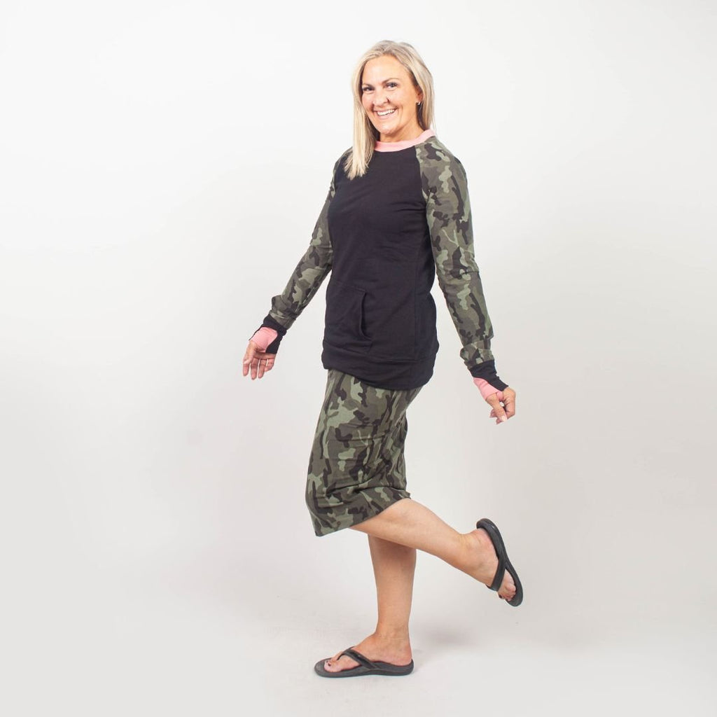 Camo Crush Crew Neck - women's relaxed fit long sleeve sweatshirt with front kangaroo pocket. long torso with longer back, soft lightweight stretchy fabric for comfort. color block black body with camouflage accent sleeves and coral accent neckline. black accent sleeve cuff with coral accent thumbhole. shown in size medium women. Paired with camouflage pencil skirt shown in size large