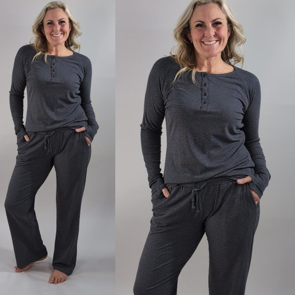 A woman wearing a dark grey long sleeve, semi-fitted, henley top with thumbholes. shown in size medium. paired with dark grey ribbed wide leg pants in size medium. 