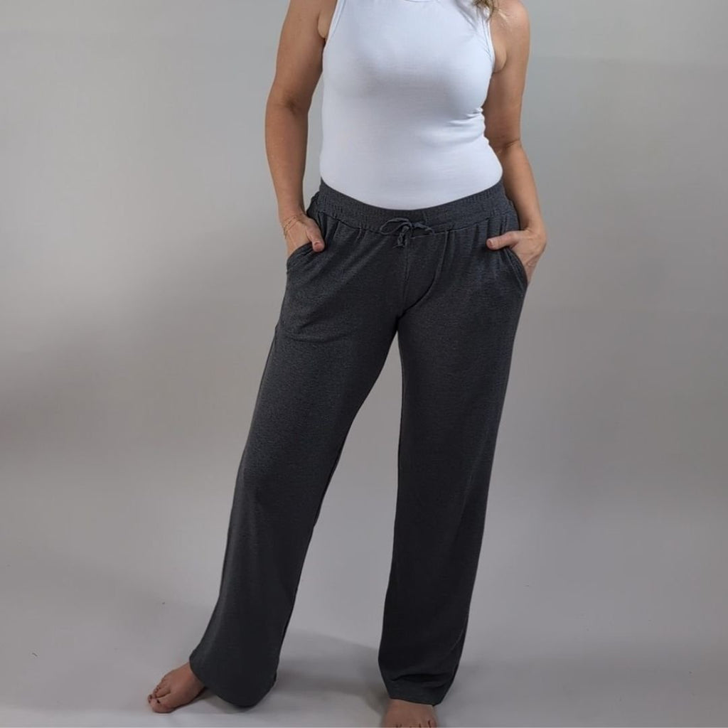A woman wearing dark grey ribbed wide-leg pants with a relaxed fit. paired with ribbed white tank top. shown in size medium. 