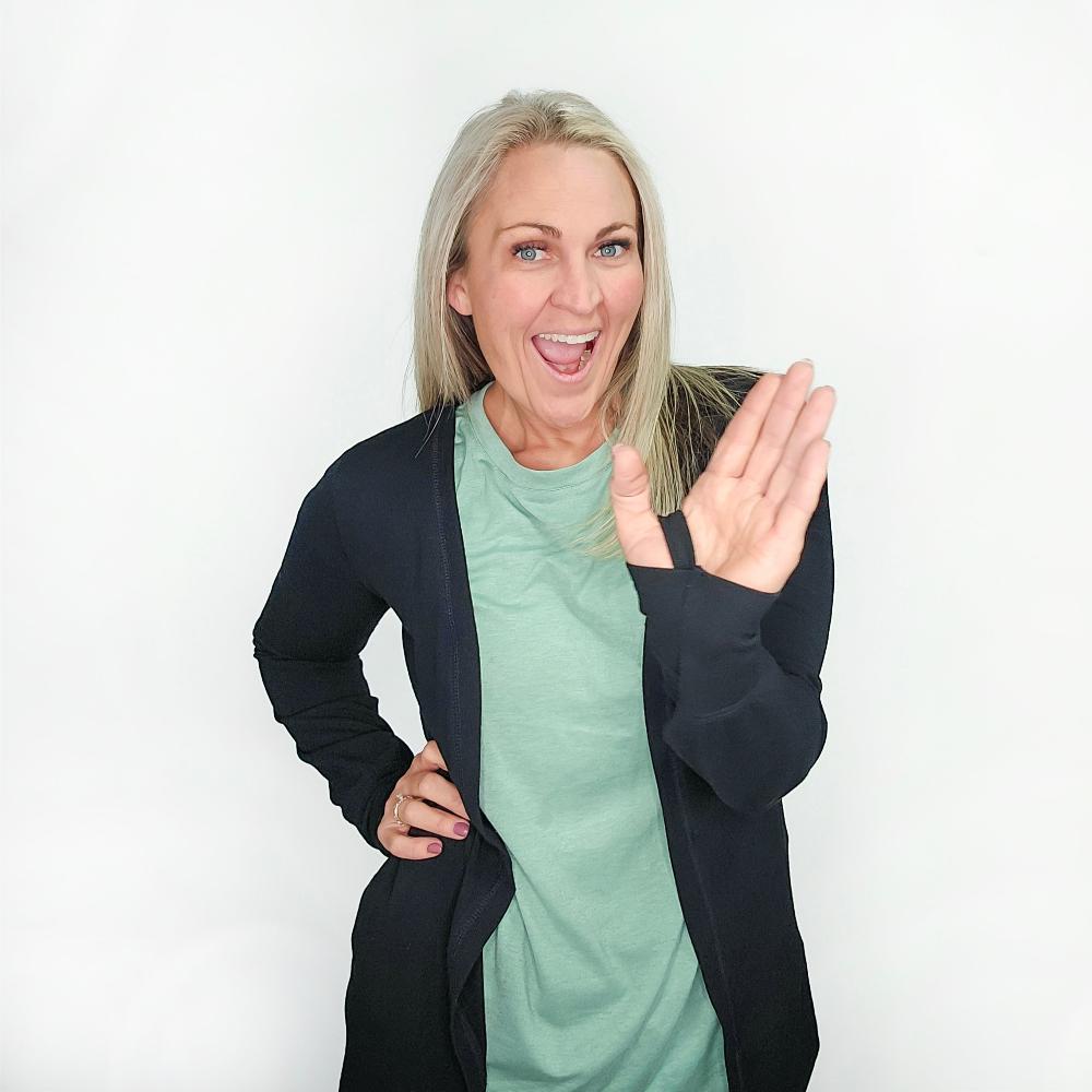 A woman wearing a black open cardigan with thumbholes, no buttons or pockets, paired with a Cadet Studio Crew shirt. Shown in size medium
