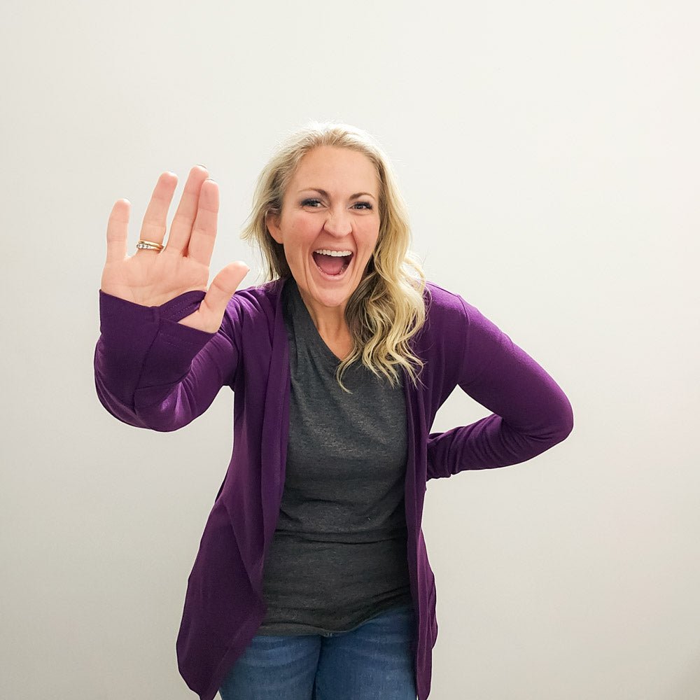 A woman wearing a purple open cardigan with long sleeves and thumbholes. shown in size medium