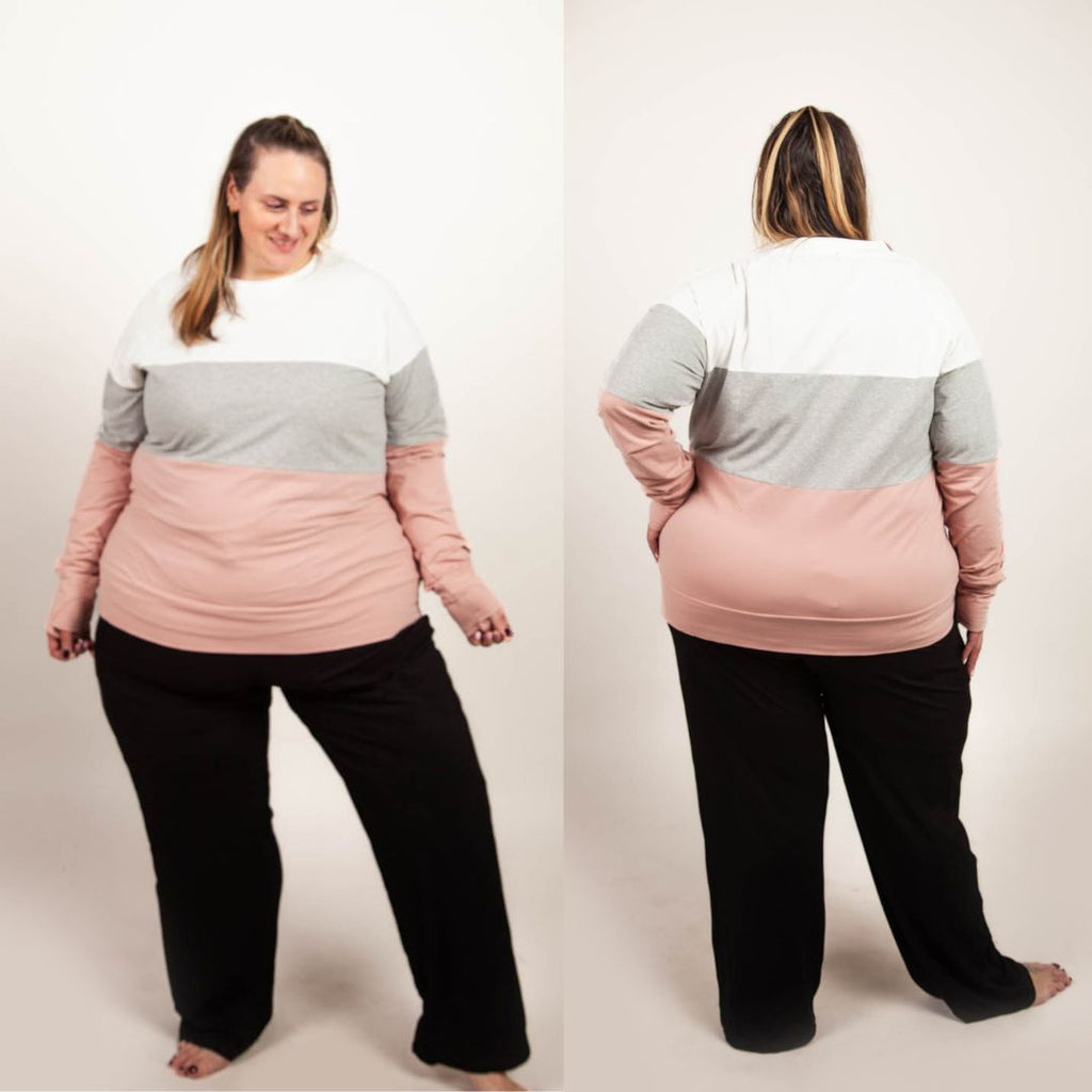 A woman wearing a tri-color crew neck sweatshirt in white, gray, and pink with long sleeves that have thumbholes. shown in size 3XL
