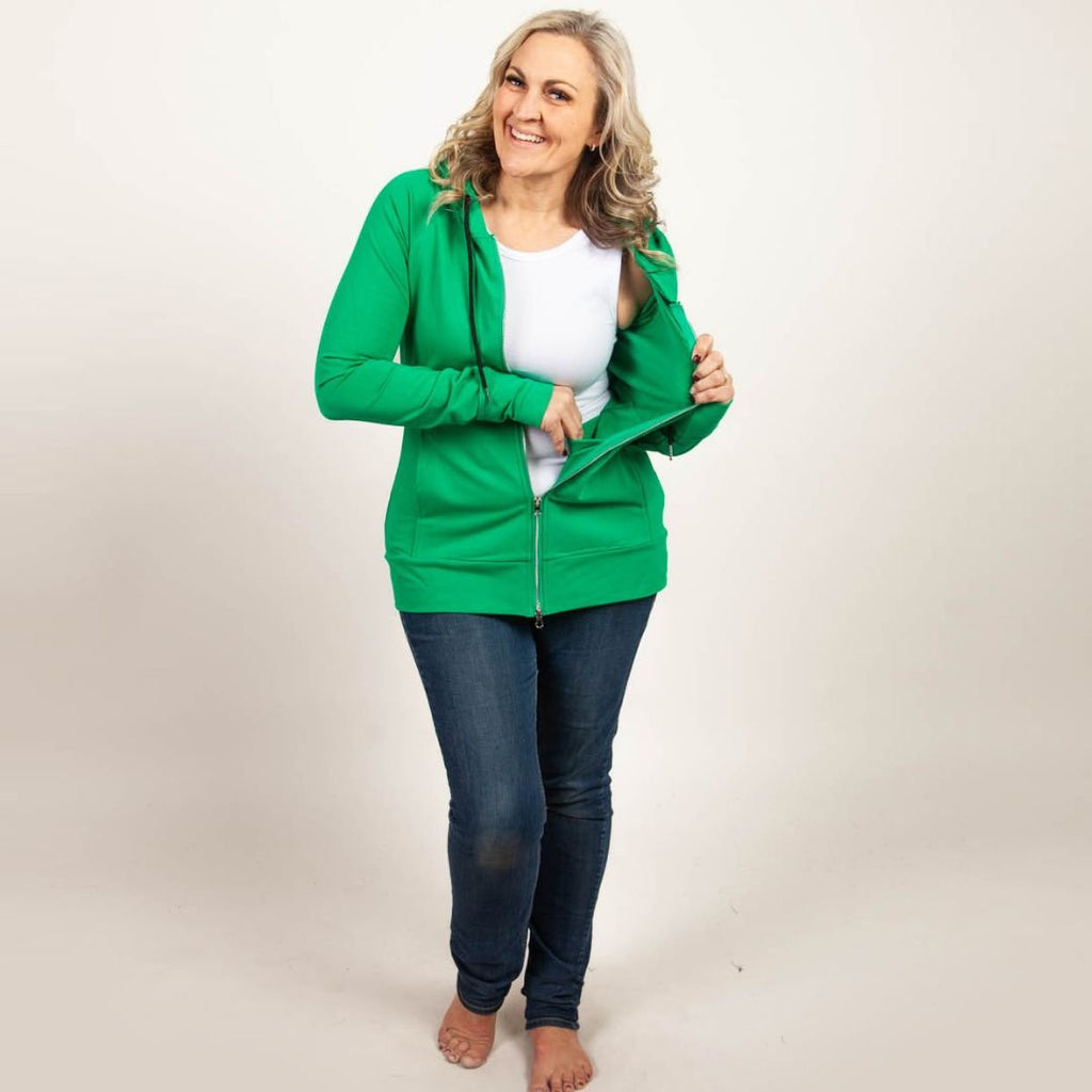 A woman wearing a green full zip hoodie with a hood, thumbholes, and a two-way zipper. shown in size medium