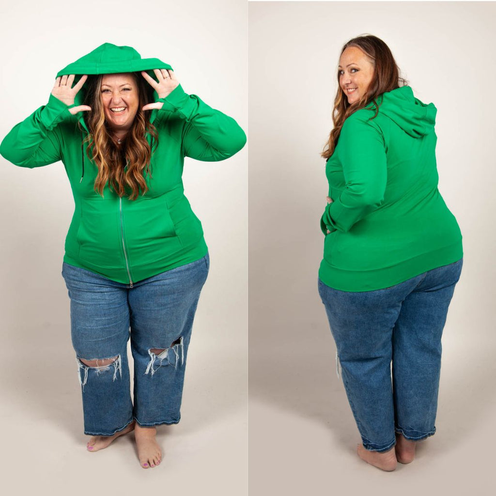 A woman wearing a green full zip hoodie with a hood, thumbholes, and a two-way zipper. shown in size 3XL