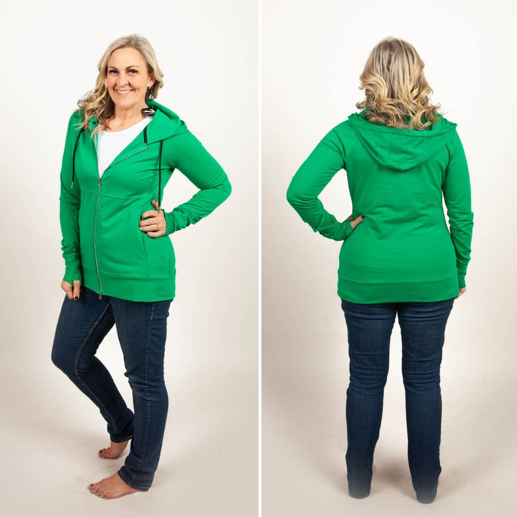 A woman wearing a green full zip hoodie with a hood, thumbholes, and a two-way zipper. shown in size medium