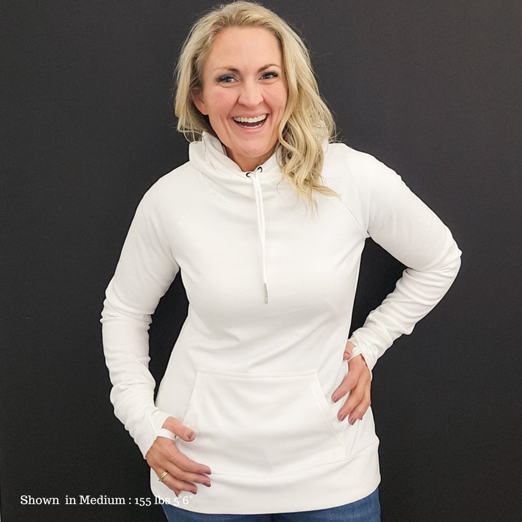 A woman wearing a white pullover hoodie with a hood, featuring a kangaroo front pocket and thumbholes on the sleeves. shown in size medium