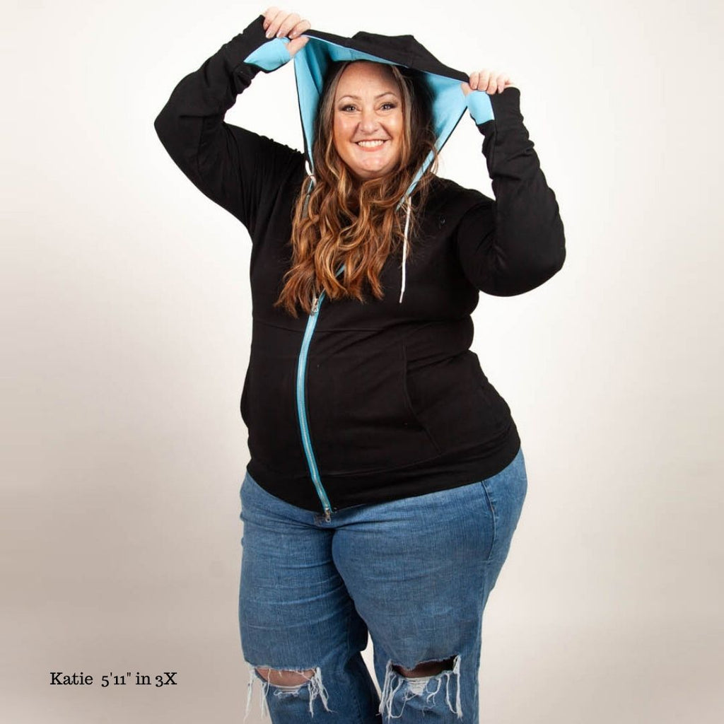 A woman wearing a black full-zip hoodie with medium blue accents. thumbholes and pockets. shown in size 3XL