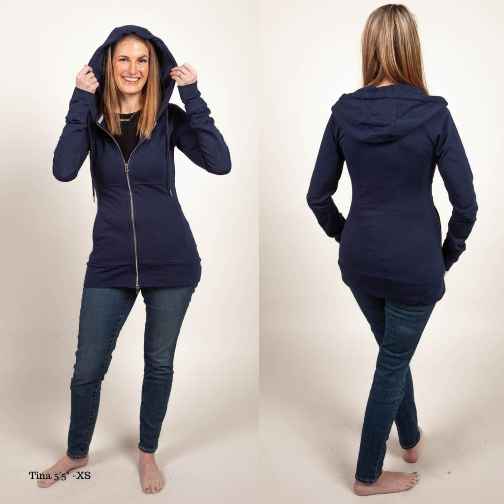 A woman wearing a navy full zip hoodie with a hood, thumbholes, and pockets. shown in size XS