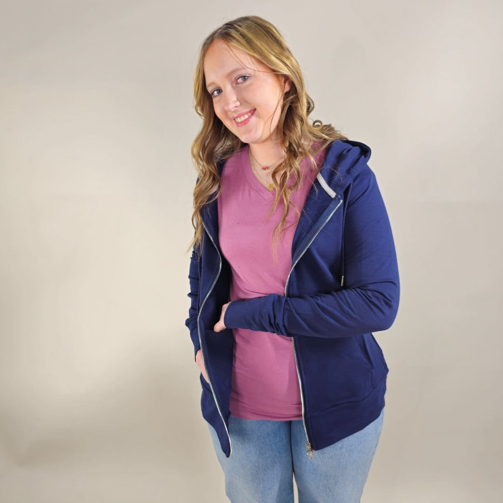 A woman wearing a navy full zip hoodie with a hood, thumbholes, and pockets. shown in size medium