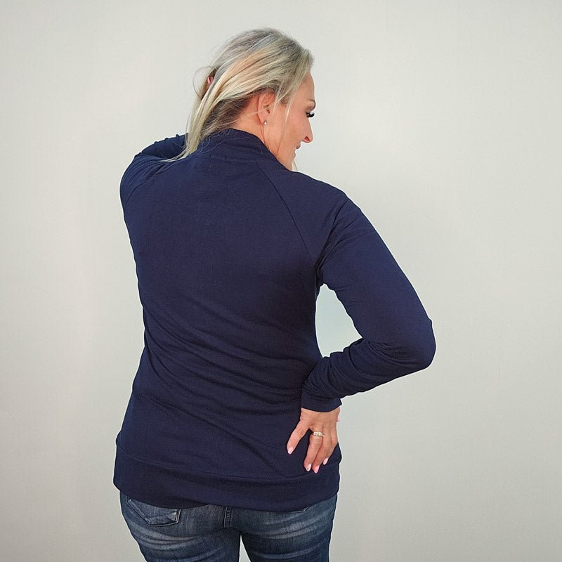 A woman wearing a navy blue hoodless jacket with a stand collar, full front zipper, and thumbholes. shown in size medium