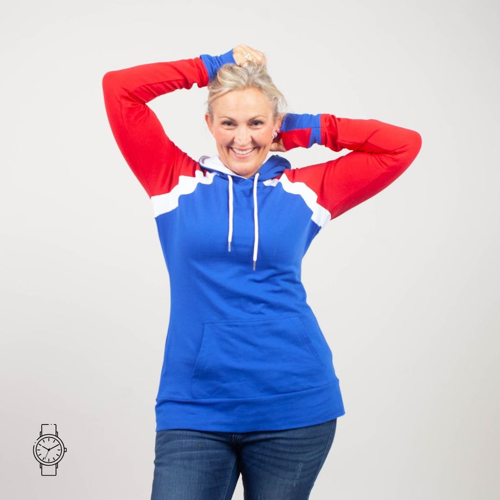 Woman wearing a blue and red hoodie with white accents, kangaroo pocket, blue sleeve watch cuffs, and red accent thumbholes. shown in size medium