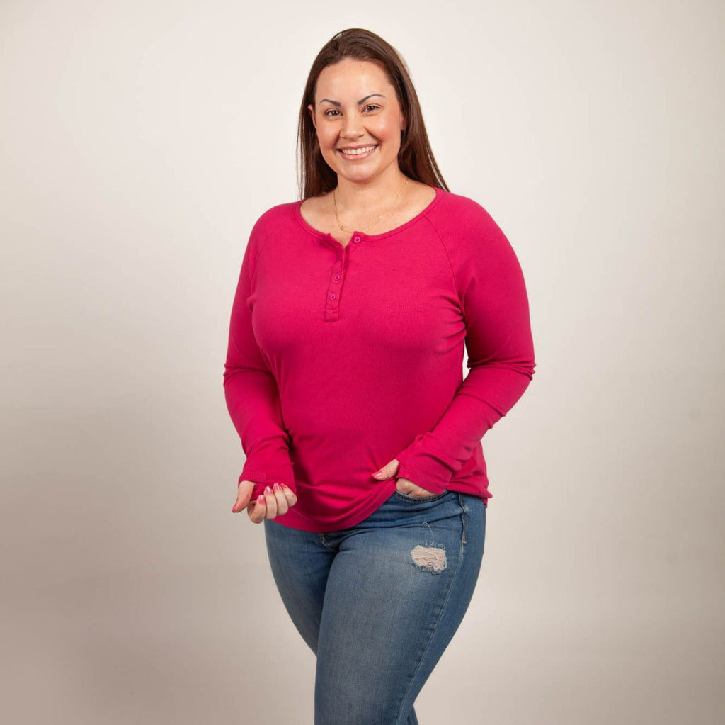 A woman wearing a raspberry red long sleeve, semi-fitted, henley top with thumbholes. shown in size large