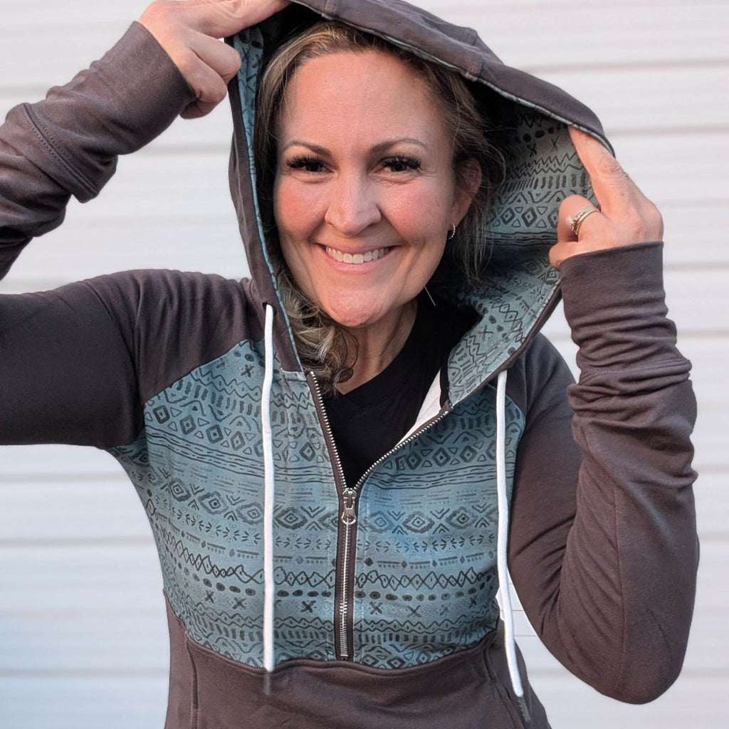 River hoodie half zip with blue azteck top and grey sleeves, bottom half and thumbholes shown in on a women in size M close up 
