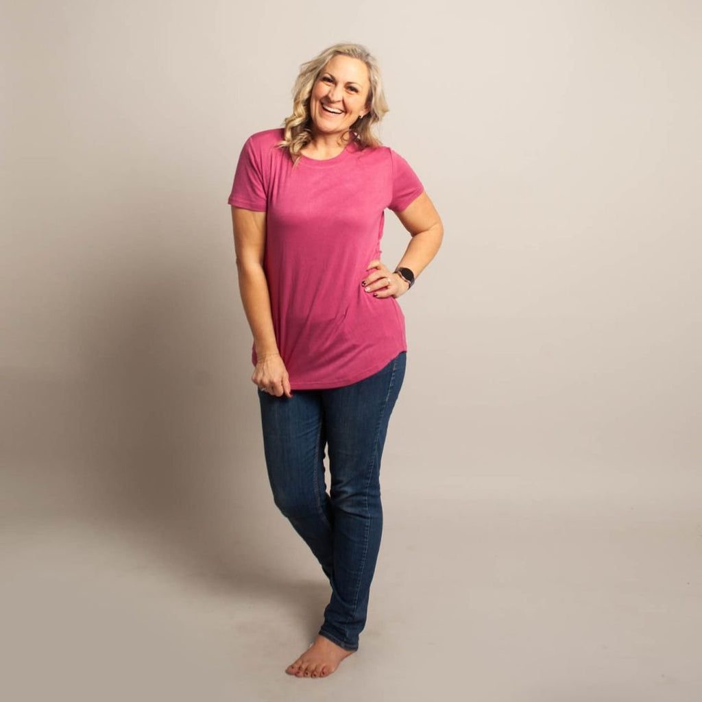 A woman wearing a pink crew neck shirt with short sleeves. shown in size medium