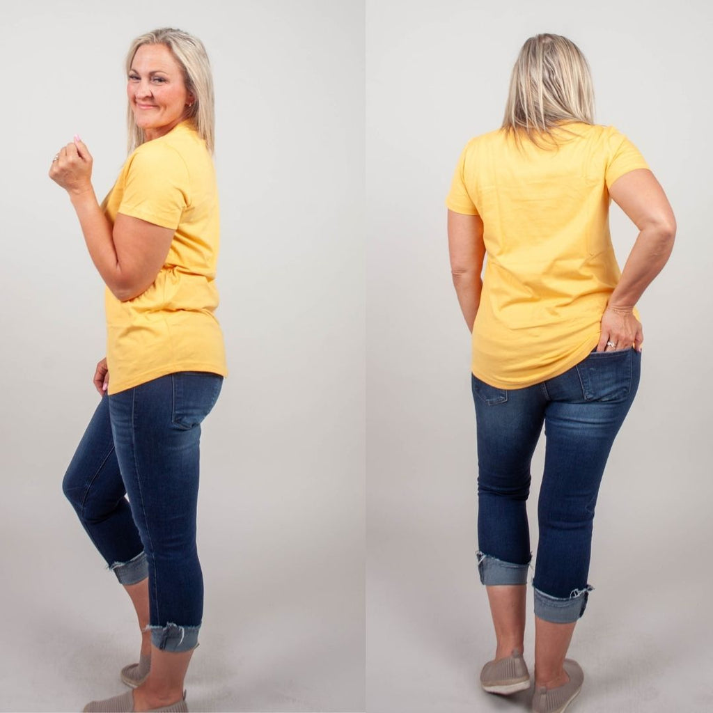 Woman wearing a sunset yellow crew neck shirt. shown in size medium