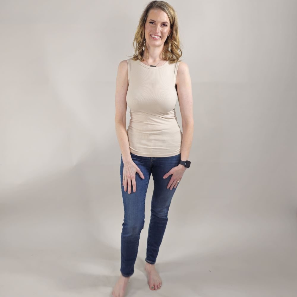 A woman wearing a tan high-neck ribbed tank top. shown in size XS