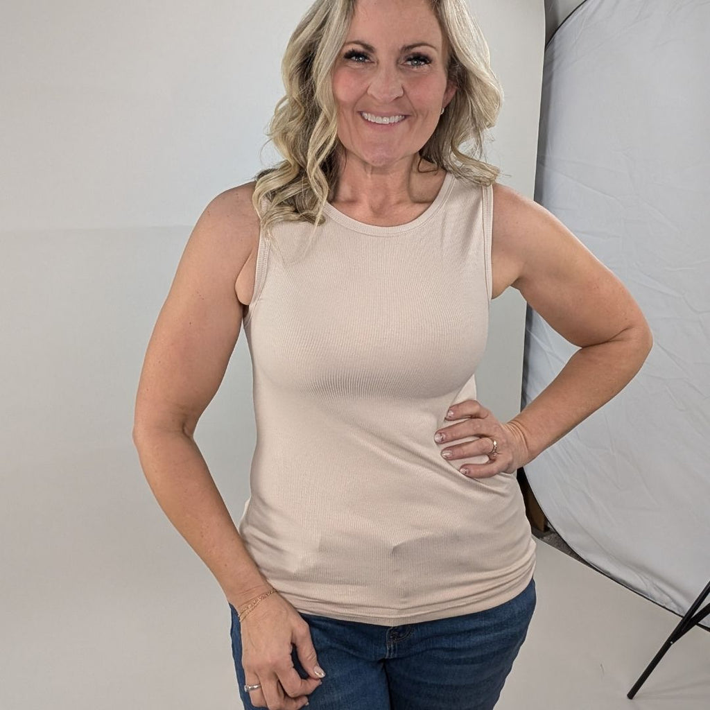 A woman wearing a tan high-neck ribbed tank top. shown in size medium