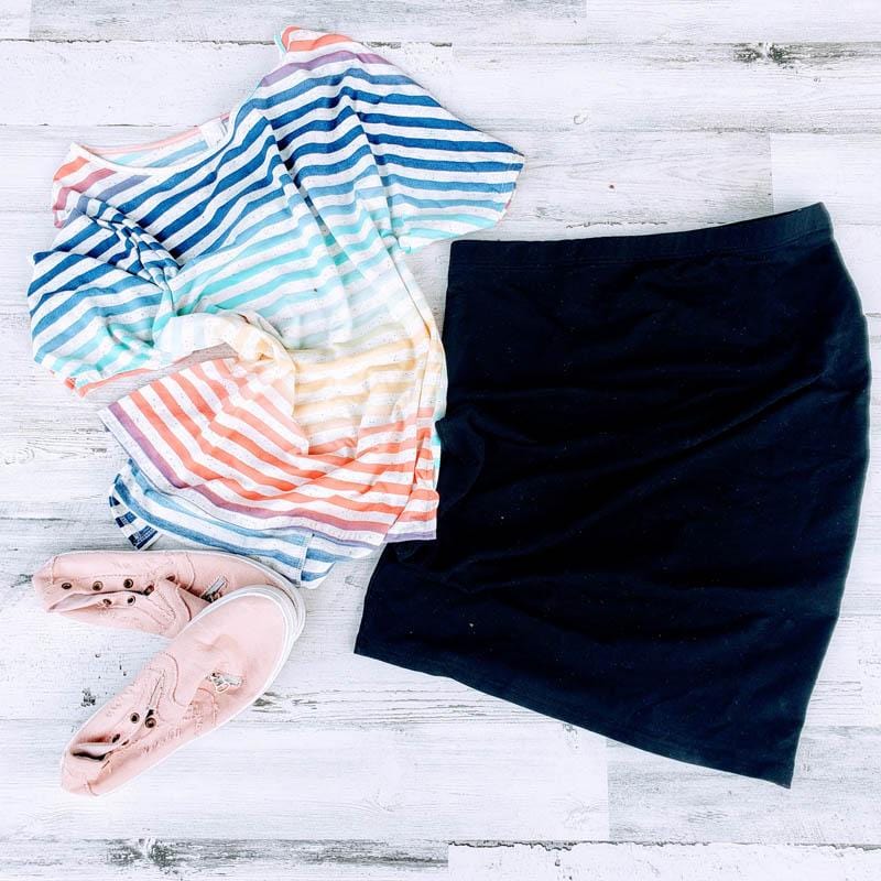 close up of a classic black knit skirt with a knee-length cut, paired with a t-shirt and sneakers. 