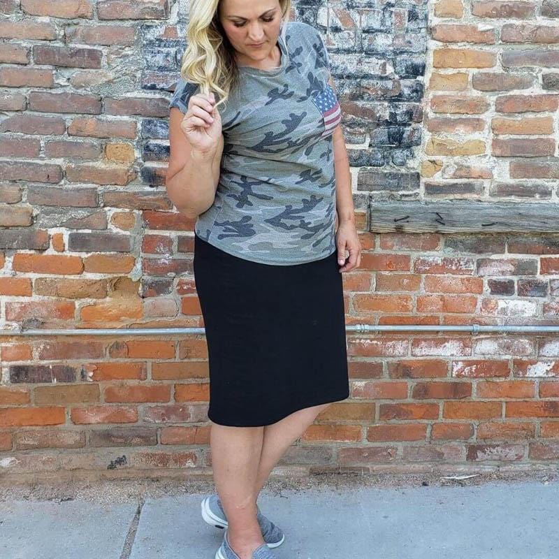 A woman wearing a classic black knit skirt with a knee-length cut, paired with a t-shirt and sneakers. 