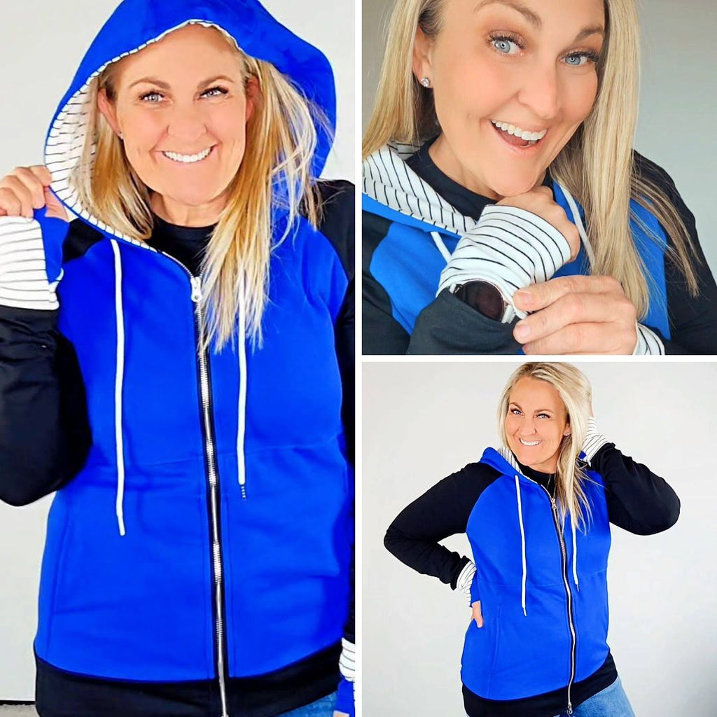 Woman wearing a blue and black hoodie with a white and black pinstripe lined hood with thumbholes and full double zipper.  features watch cuff. shown in size XL