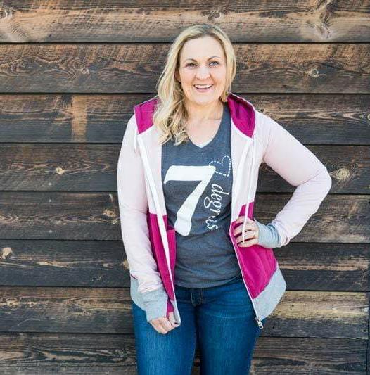 A woman wearing a color-blocked hoodie with light pink on the top, raspberry pink on the bottom, and heather gray accents. Features include side pockets, thumbholes, and raspberry pink lined hood. shown in size medium